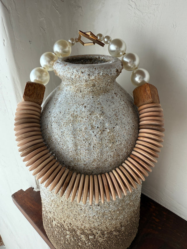 Colar com pérolas e madeira em estilo boho-chic, destacando a combinação sofisticada de materiais.