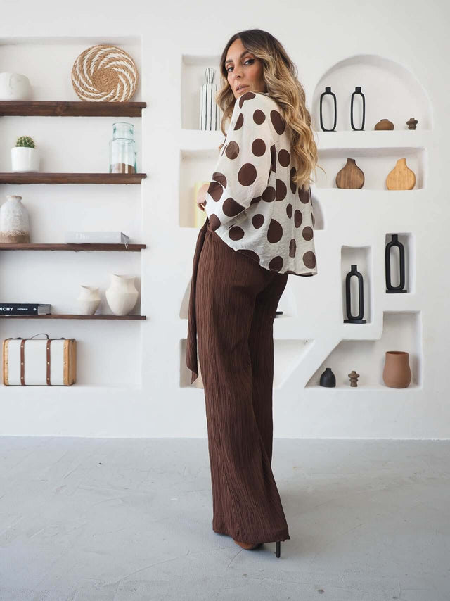 Camisa Bolas com padrão polka dots, estilo contemporâneo e elegante, vista de costas com calças castanhas.