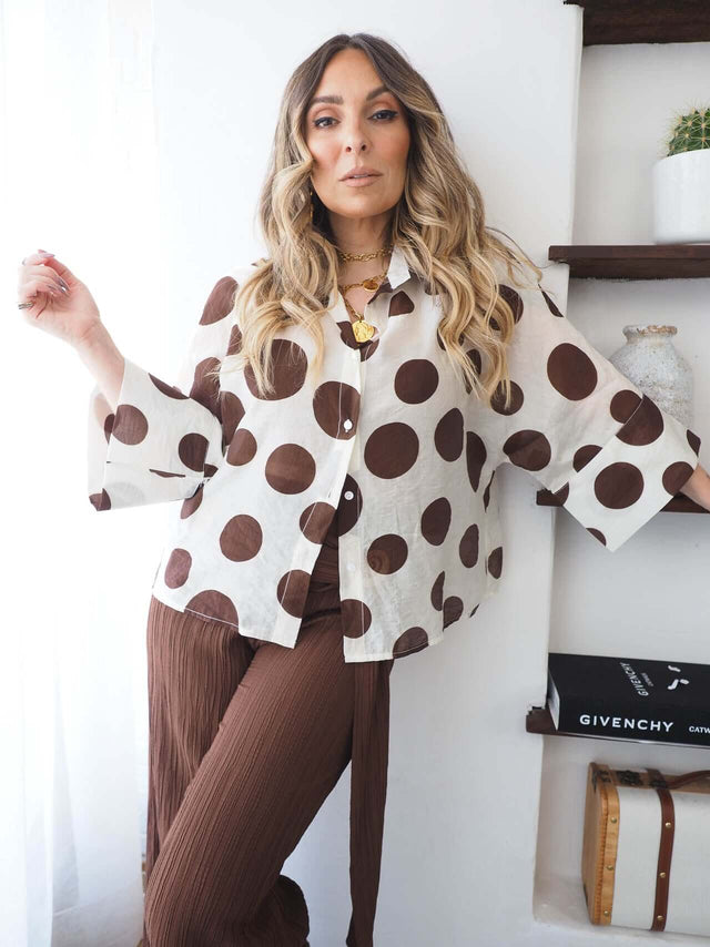 Camisa Bolas feminina com padrão polka dots, estilo elegante e contemporâneo, em ambiente moderno.