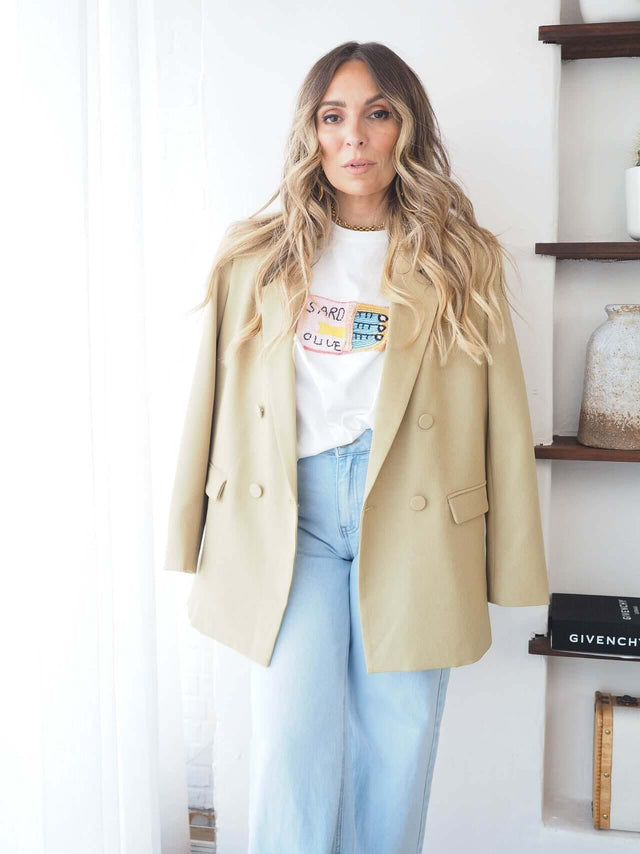 T-Shirt Com Missangas: t-shirt feminina com missangas sob um blazer elegante e calças de denim claro.