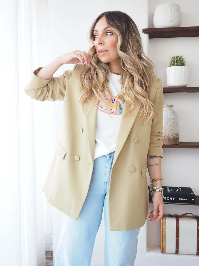 Mulher com blazer bege e T-Shirt Com Missangas, exibindo estilo contemporâneo e elegância discreta.