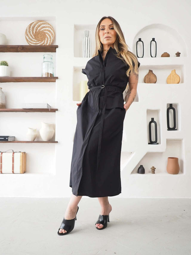 Modelo feminina usando Vestido Midi Safari Ajustável em fundo moderno, destacando estilo elegante e ajuste prático.