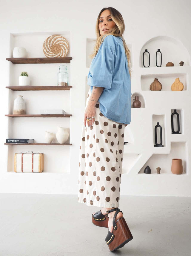 Modelo usando Calças Culote às Bolas com blusa azul, em ambiente moderno e elegante.