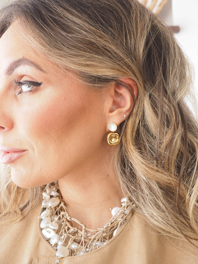 Brincos de madre-pérola com pendente dourado, destacando a elegância e sofisticação.