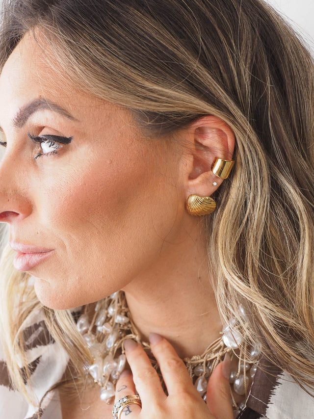 Mulher a usar earcuff largo liso em estilo moderno e minimalista, complementando o seu visual sofisticado.