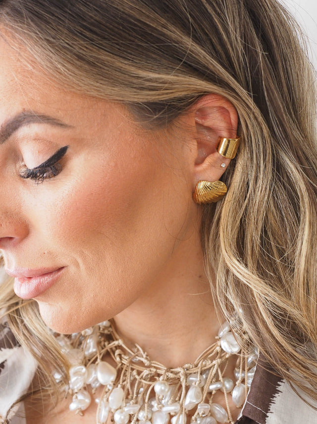 Modelo a usar um earcuff largo liso em estilo minimalista, destacando um look moderno e sofisticado.