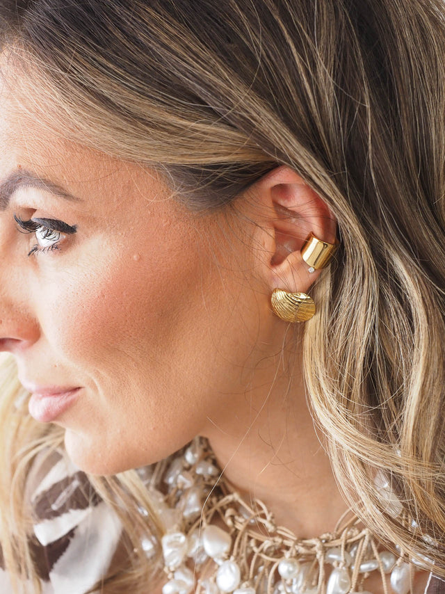 Modelo a usar earcuff largo liso dourado, destacando o design minimalista e moderno, ideal para looks sofisticados.