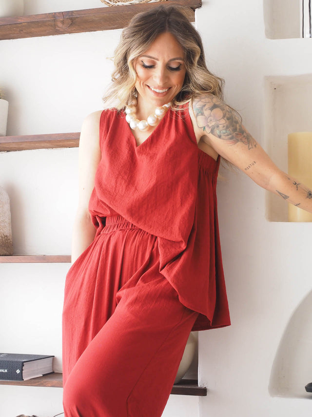 Modelo a sorrir em top básico de alça larga vermelho, combinando leveza e conforto em dias quentes.