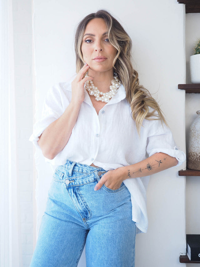 Mulher elegante com camisa de linho branca e calças azuis, destacando estilo e conforto para dias quentes.