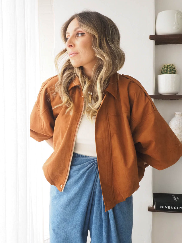 Blusão feminino oversized efeito camurça em tom mostarda, combinando com calças azuis, ideal para looks primaveris.