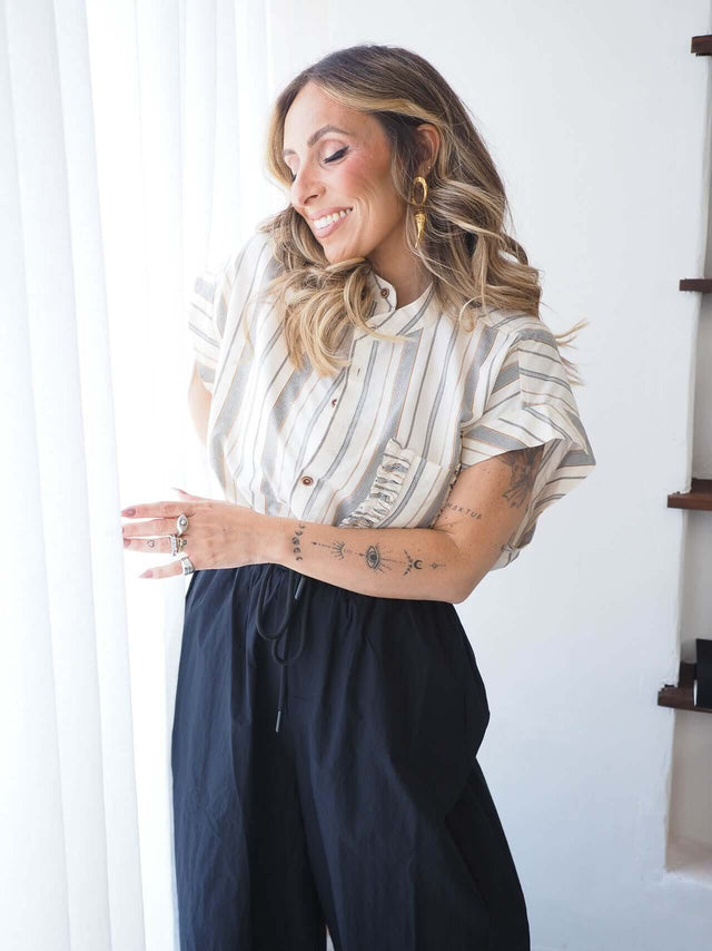 Camisa Riscas feminina oversized em linho com riscas, combinada com calças de ganga, ideal para um look descontraído.