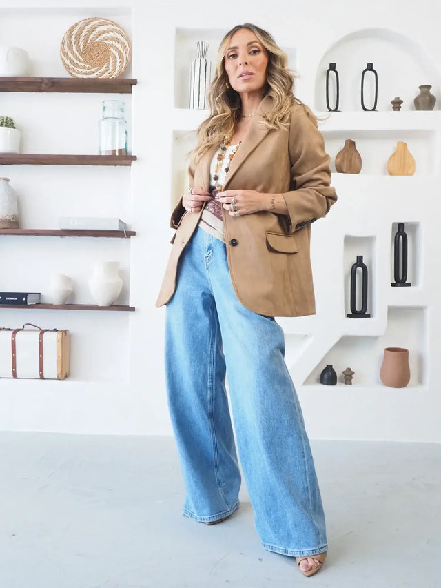 Mulher a usar calças de ganga pantalona com blazer clássico.