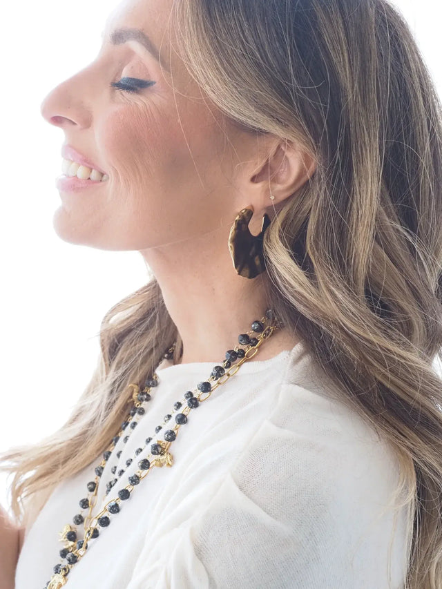 Mulher a usar brincos com textura em aço inoxidável e colar elegante.