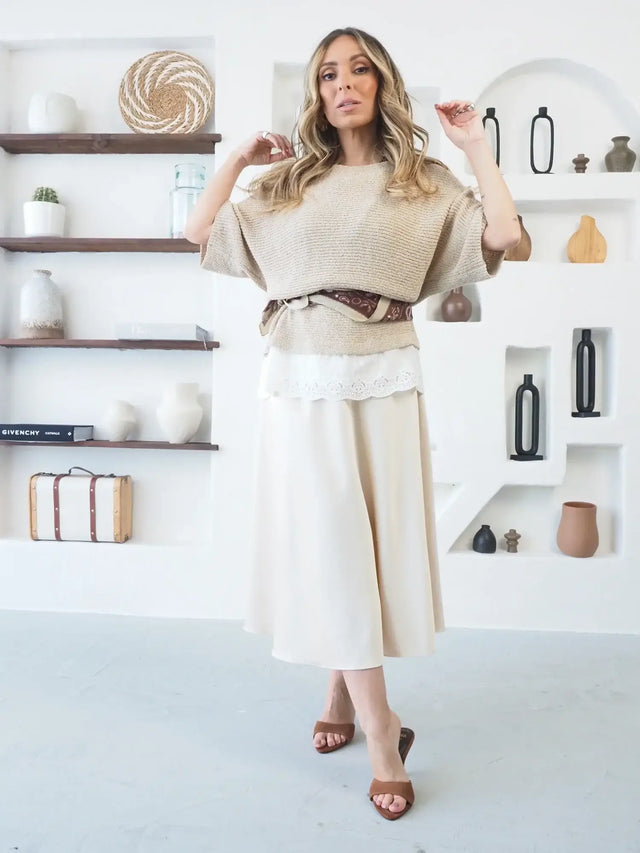 Imagem de uma mulher usando saia midi em cetim com camisola bege.
