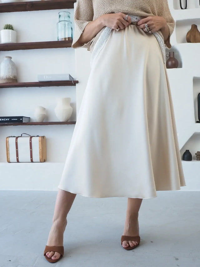 Saia Midi em Cetim de cor clara com caimento fluido e elegante.