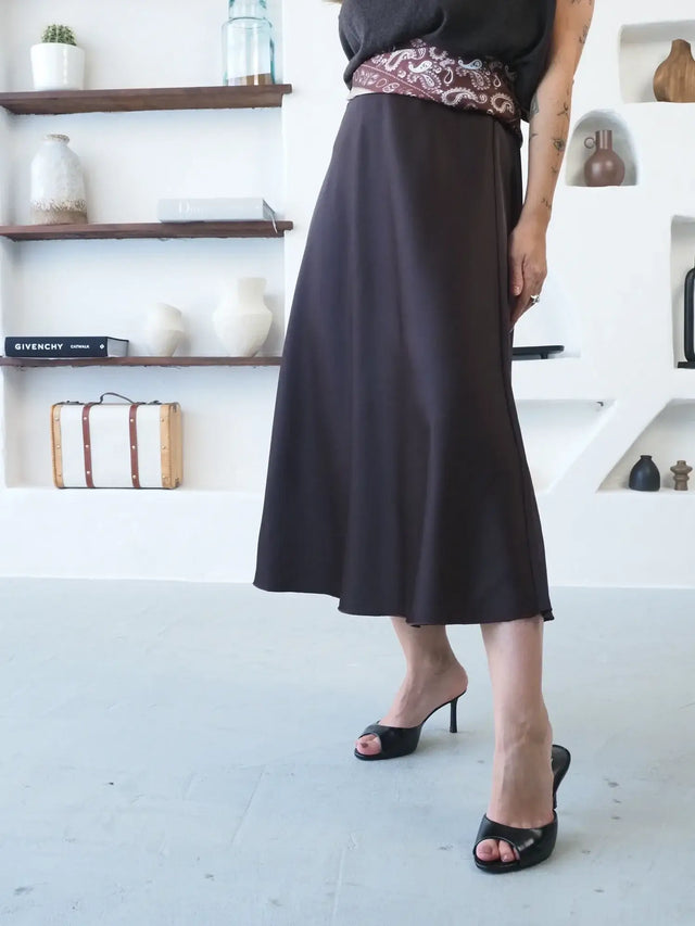 Saia Midi em Cetim em tom escuro com caimento fluido e elegante.