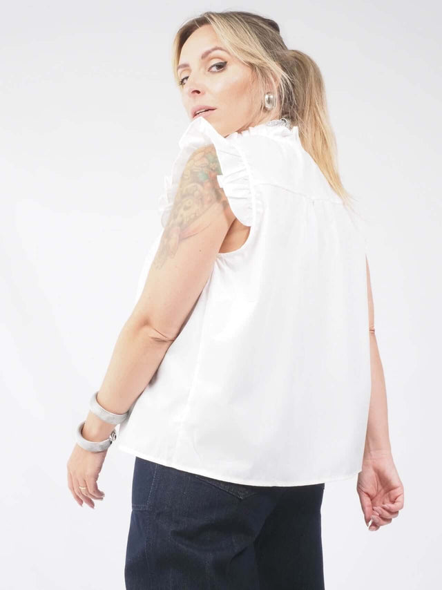 A blusa de manga cava com folho está disponível em duas cores: preto e branco