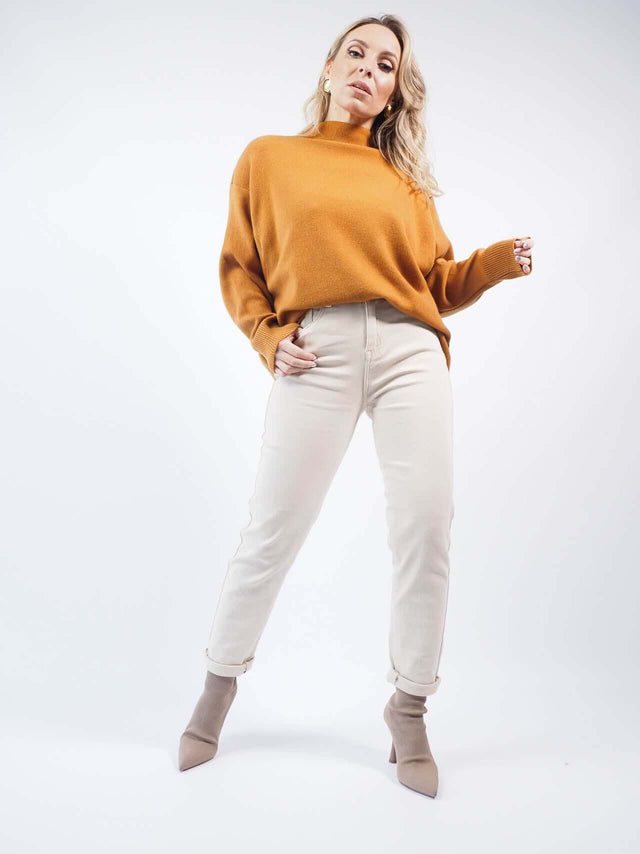 Calças bege, combinadas, com uma camisola de malha camel.