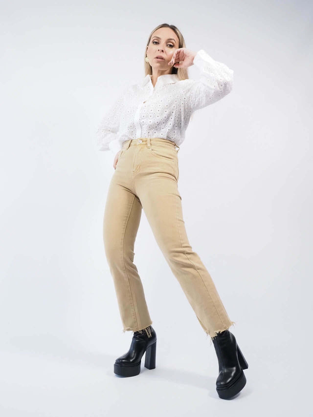 Calças de ganga bege combinada com uma camisa branca por dentro da calça.