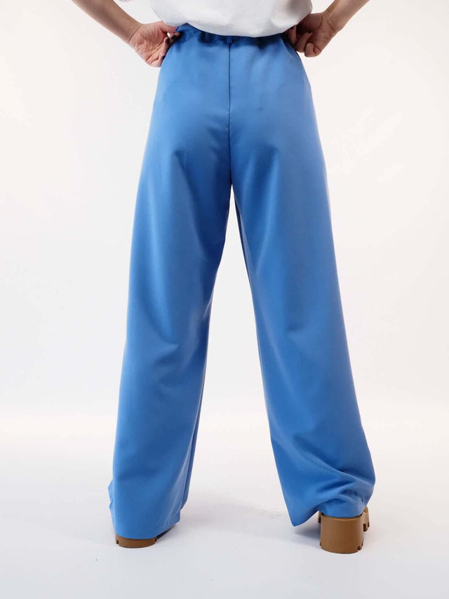 Calças pantalonas em azul com pormenor visto de trás.