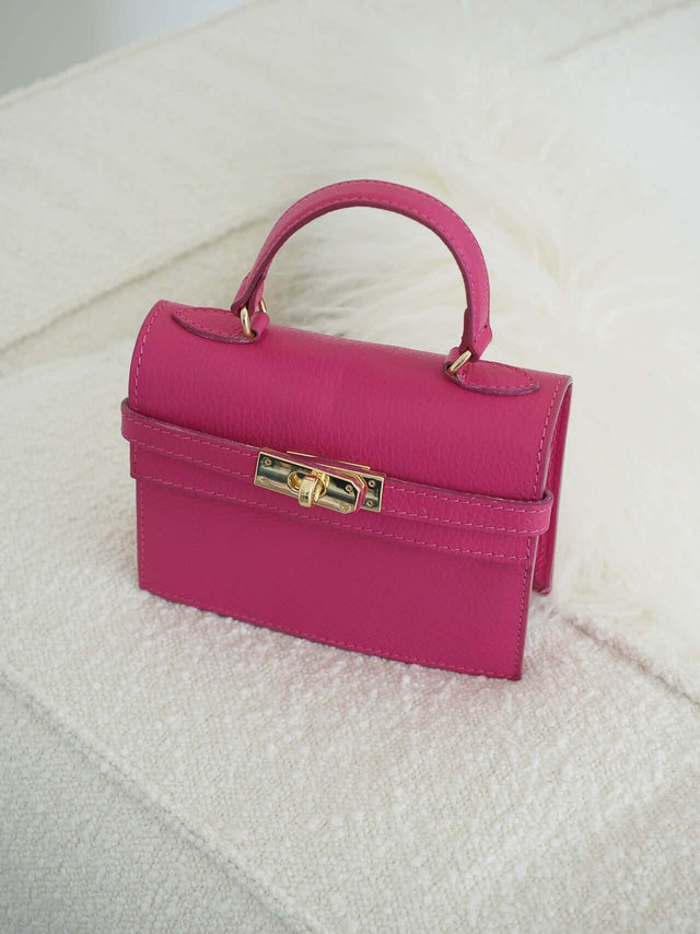 Mala com fecho de metal e pode ser usada com uma alça de mão ou de ombro (tira-colo).