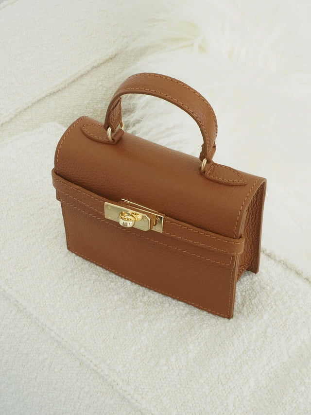 Mala com fecho de metal e pode ser usada com uma alça de mão ou de ombro (tira-colo).