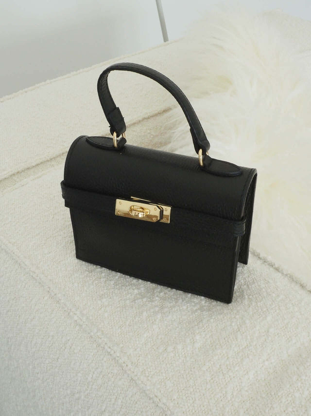 Mala com fecho de metal e pode ser usada com uma alça de mão ou de ombro (tira-colo).