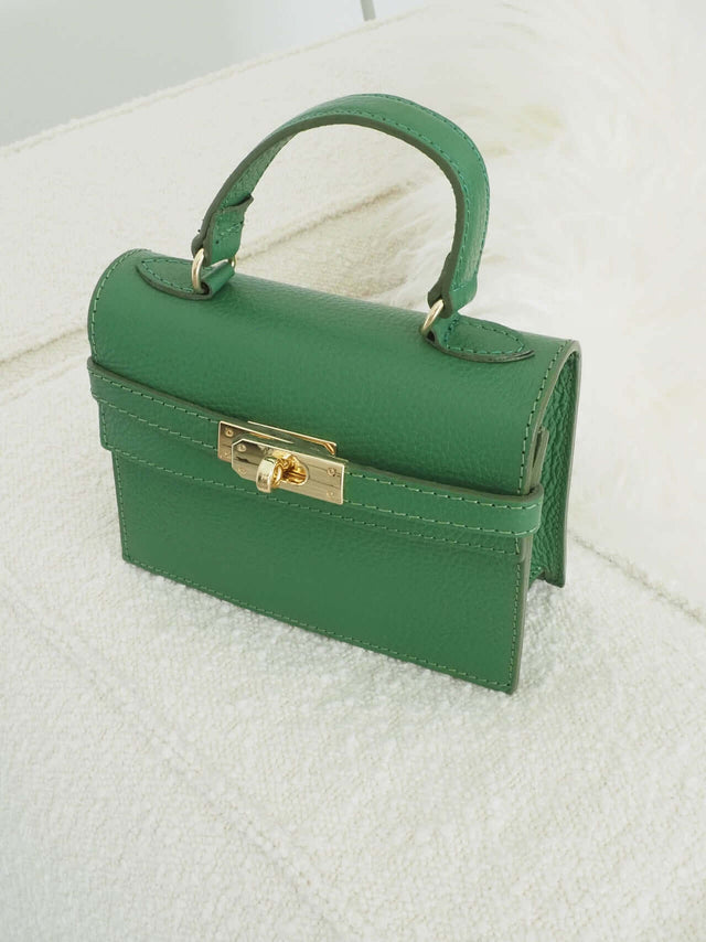 Mala com fecho de metal e pode ser usada com uma alça de mão ou de ombro (tira-colo).