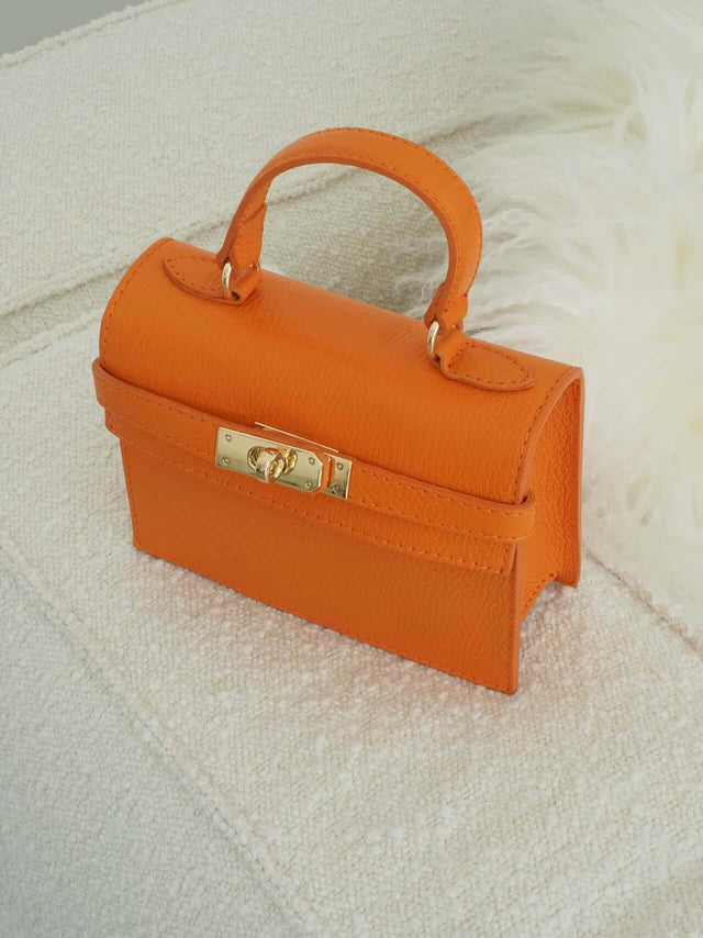 Mala com fecho de metal e pode ser usada com uma alça de mão ou de ombro (tira-colo).