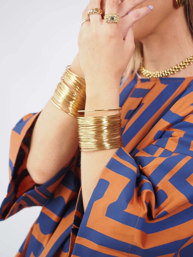 A bracelete dourada é versátil e pode ser combinada com outros acessórios para criar um visual completo.