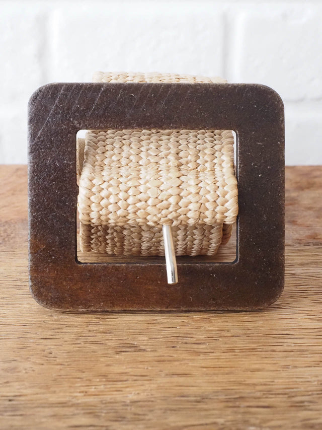 Um cinto de ráfia elástico que possui uma fivela quadrada de madeira - perfeito para completar um look sem esforço e cheio de estilo.
